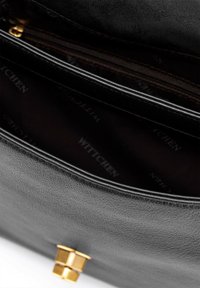 Sac en cuir noir avec une finition texturée, doté d'une fermeture en métal doré et d'un intérieur sombre avec un motif répétitif "Wittchen".