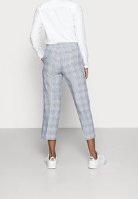 Blårutig cropped byxor med avspänt snitt, som har bakfickor och är parat med vita sneakers. Materialet verkar lätt.