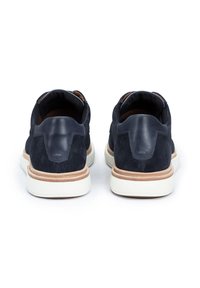 Baskets en suède marine avec des accents en cuir, dotées d'un design low-top, d'une semelle en caoutchouc blanche et de détails contrastants en tan au niveau du talon.
