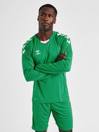 Grøn atletisk trøje og shorts lavet af glat, fugttransporterende stof. Har hvide detaljer og Hummel-logoet på brystet.