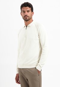 Lichtcrème lange mouw pullover met een ritssluiting in de nek, geribde manchetten en een normale pasvorm. Zachte textuur en naadloos ontwerp met minimale accenten.