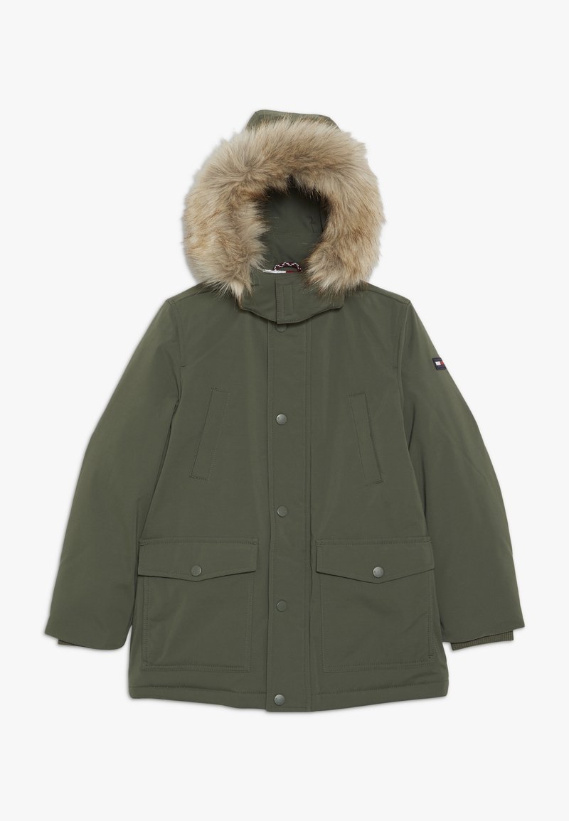 Parka vert olive avec capuche bordée de fourrure, multiples poches avant et fermetures à pression. Texture lisse, éléments de design fonctionnels.