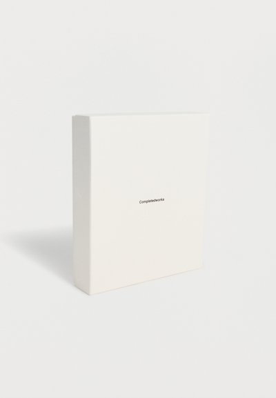 Λευκό ορθογώνιο κουτί σε όρθια θέση με τη λέξη «Completedworks» τυπωμένη με μικρό μαύρο κείμενο στο κέντρο της μπροστινής όψης.
