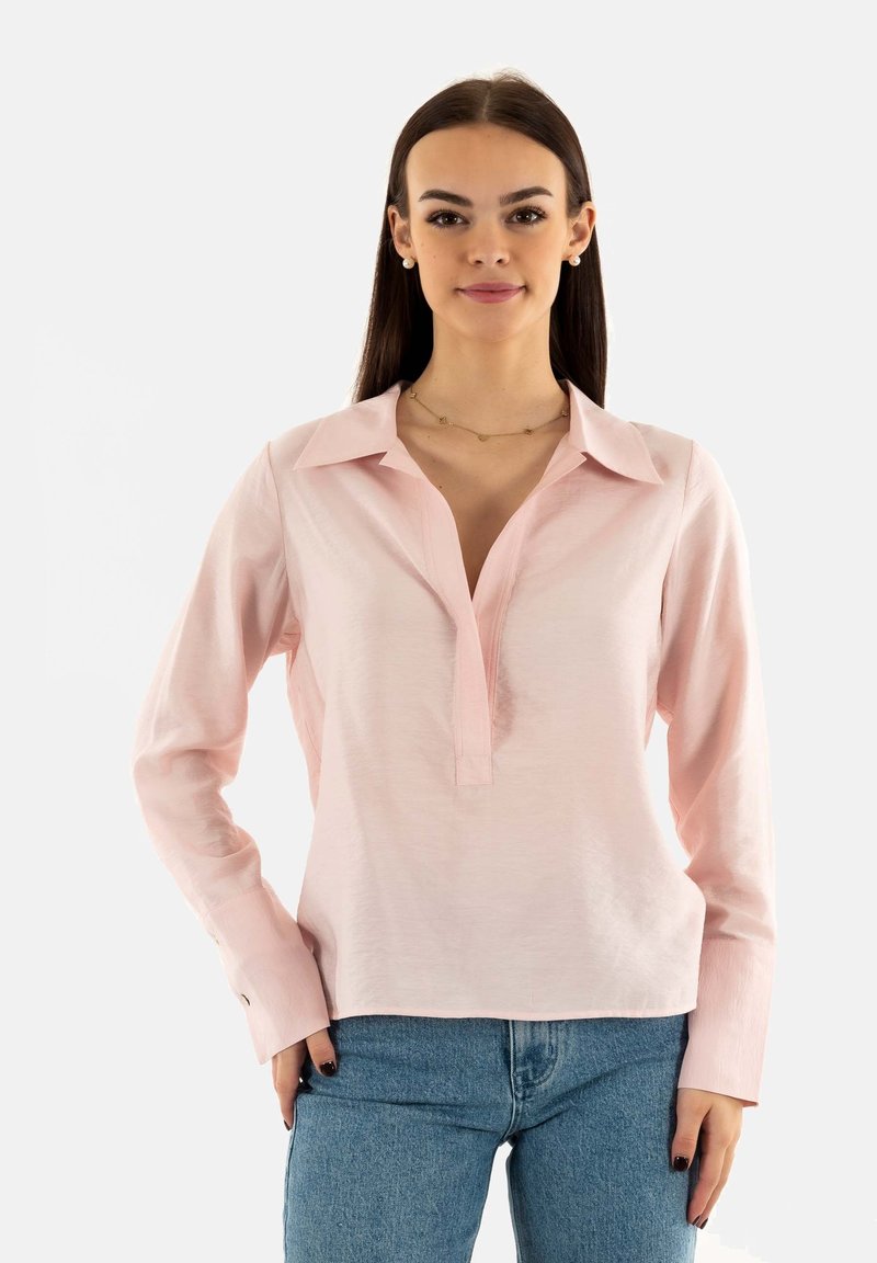 Camisa de manga larga rosa claro con cuello, escote abotonado y puños; hecha de una tela suave con un ligero brillo. Combinada con jeans azules.