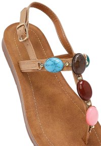 Sandalo in finta pelle scamosciata marrone con suola piatta, caratterizzato da ovali gemme colorate e accenti in oro nel design a T-strap.