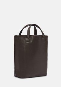 Brązowa skórzana torba tote o wyraźnie prostokątnym kształcie, z dwiema krótkimi rączkami, gładką fakturą i subtelnymi detalami w postaci przeszyć.