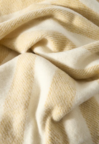 Μαλακό, κρεμ χρώματος μάλλινο ύφασμα με ομαλές πτυχές και διακριτικό κίτρινο λοξό ριγέ μοτίβο.