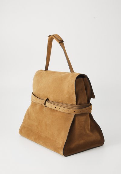 Geantă de mână din suede bej cu un design structurat, având un accent de curea, textură netedă și bază rotunjită.