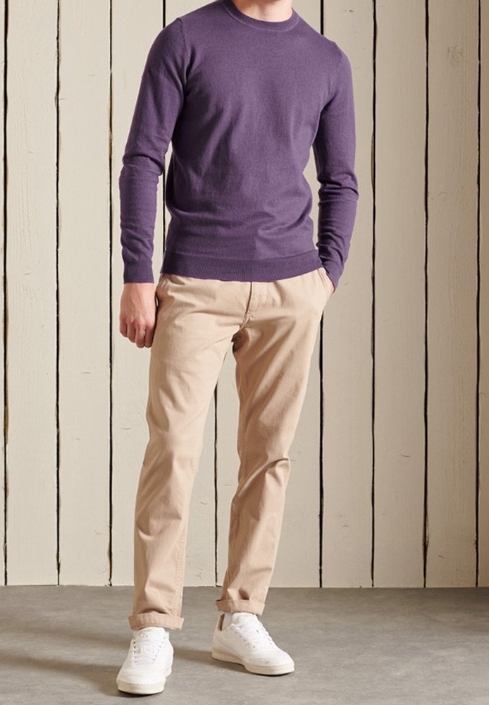 Pull violet à col rond associé à un pantalon chino beige et des baskets blanches. Le pull présente une coupe ajustée et des poignets côtelés.