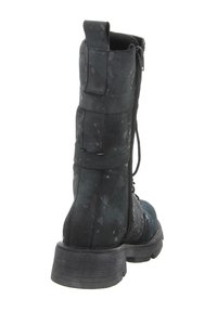 Schwarzer Knöchelstiefel aus strukturiertem Material mit Spritzmuster, ausgestattet mit seitlichem Reißverschluss und klobigem Absatz. Die Rückansicht hebt die Nähte hervor.