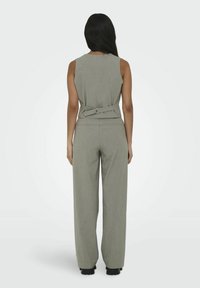 Grå ærmeløs jumpsuit med en tætsiddende overdel, bæltestroppdetalje i taljen, brede bukser og baglommer, lavet af et blødt stof.