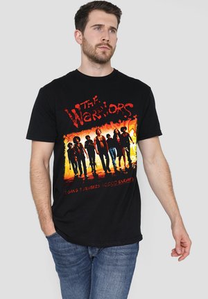 Black cotton t-shirt featuring a colorful graphic print of "The Warriors" with characters and text against a fiery background.