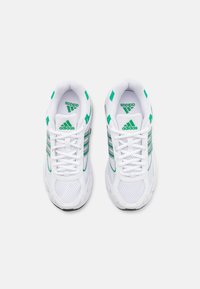 Scarpe da ginnastica bianche con accenti verdi, parte superiore in rete e tre strisce orizzontali. Presentano un design con lacci e suola texturizzata.