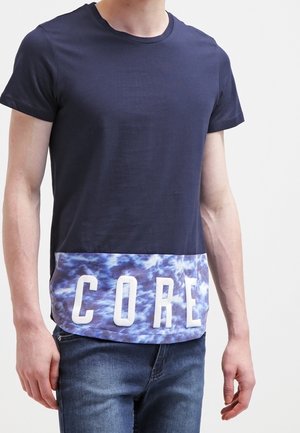 Camiseta de manga corta azul marino con un estampado texturizado de olas azules y "CORE" en letras blancas en negrita en la parte inferior.