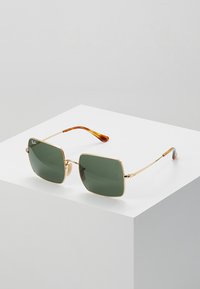 Occhiali da sole con montatura in metallo dorato e lenti verde scuro. Lenti quadrate, punte color marrone e aste sottili con dettagli del logo.