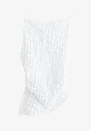 Bílá texturová tkanina s krčeným vzorem, zavěšená asymetricky. Obsahuje dvě visící smyčky nahoře pro upevnění.