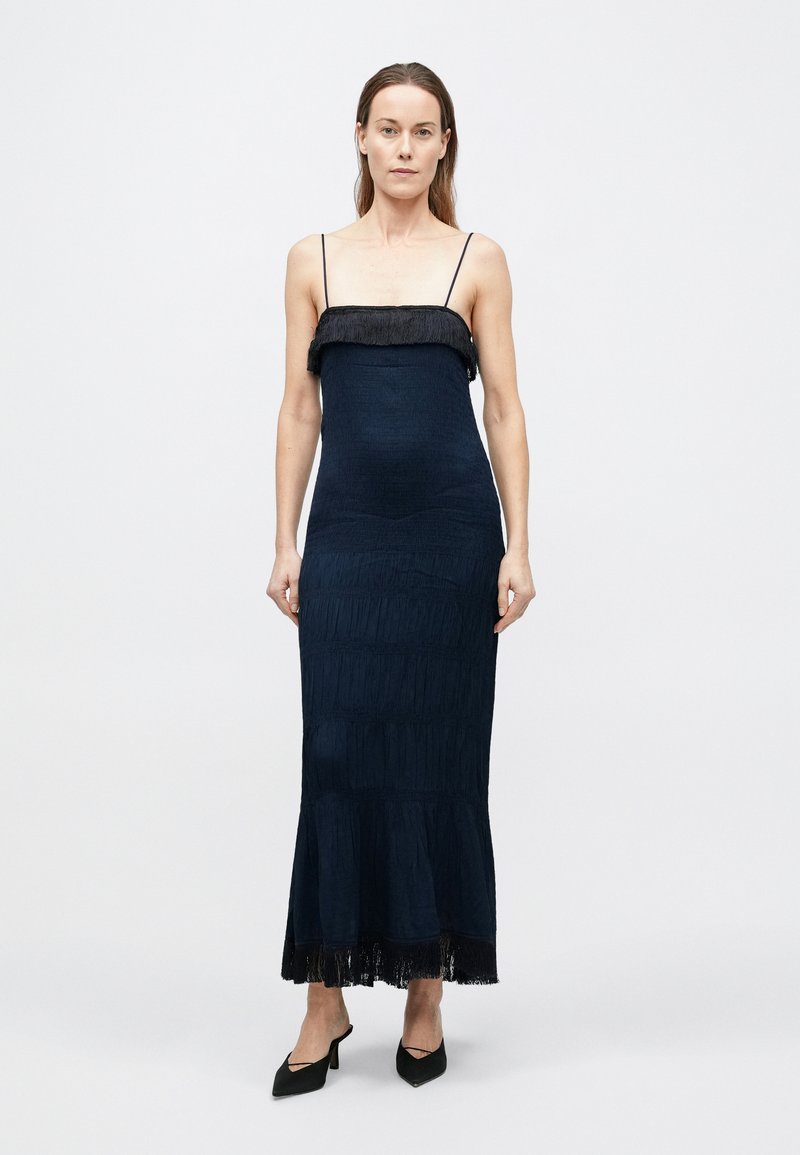 Marineblå maxikjole med en tætsiddende overdel, frynset kant og tynde skulderstropper. Fremstillet af et struktureret stof med lodrette striber.