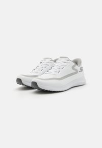 Baskets de sport blanches avec une tige en textile lisse, accents gris, bout arrondi et semelle extérieure en caoutchouc texturé. Elles disposent de lacets tissés et d'un détail de logo.