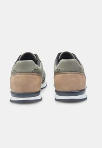 Žalios ir tan spalvos zomšiniai sportbačiai su juodu tinkliniu liežuviu, paminkštinta apykakle, balto ir juodo dryžuoto vidurio padu ir tekstūruota kulno detale.