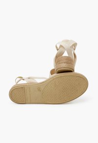 Sandali espadrilles beige con fasce incrociate in tessuto e tacco intrecciato. La soletta presenta un motivo di grip testurizzato. Fabbricati in Spagna.