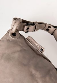Borsa in pelle grigia con finitura testurizzata, dotata di una tracolla removibile, dettagli in metallo e un'etichetta del marchio visibile.