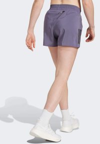 Lila sportliche Shorts mit einem elastischen Bund, einer Gesäßtasche und schwarzen seitlichen Akzenten. Aus leichtem, atmungsaktivem Stoff gefertigt.