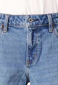 Lichtblauwe denim jeans met een klassieke pasvorm, voorzien van oranje stiksels, een metalen knoopsluiting en een front pocket.