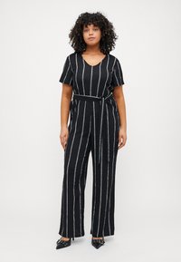 Black striped jumpsuit with a V-neck, short sleeves, a tie belt at the waist, and wide-leg silhouette. Features multi-colored vertical stripes.