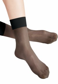 Przezroczyste brązowe pończochy sięgające do kostek z czarną elastyczną opaską u góry. Przezroczysty materiał o gładkiej fakturze i otwartym palcem.