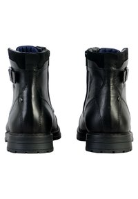 Bottes de cheville en cuir noir avec une finition lisse, des élastiques sur les côtés et une semelle en caoutchouc robuste. Présente un accent de boucle sur chaque botte.