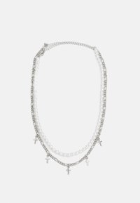 Collar de tres capas que presenta cadenas de plata, perlas blancas y pequeños colgantes de cruz de plata. El diseño es elegante con un contraste de materiales mixtos.