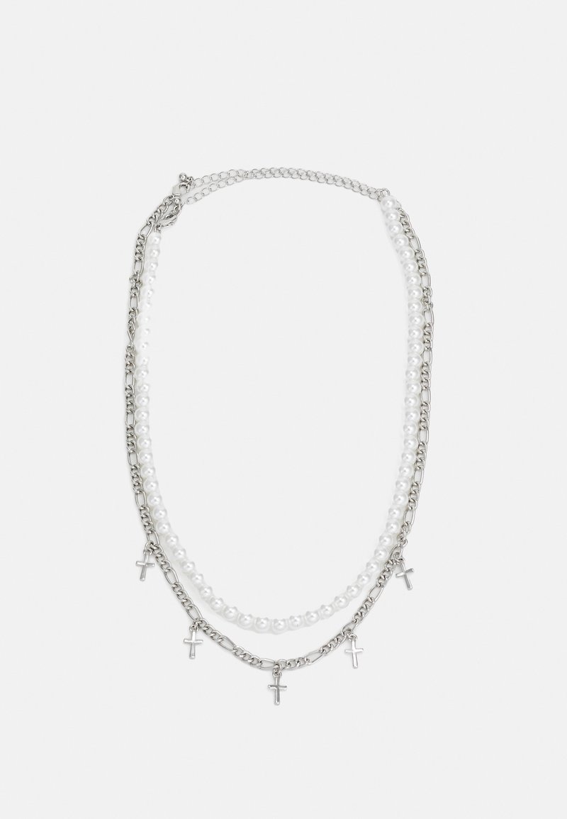 Collar de tres capas que presenta cadenas de plata, perlas blancas y pequeños colgantes de cruz de plata. El diseño es elegante con un contraste de materiales mixtos.