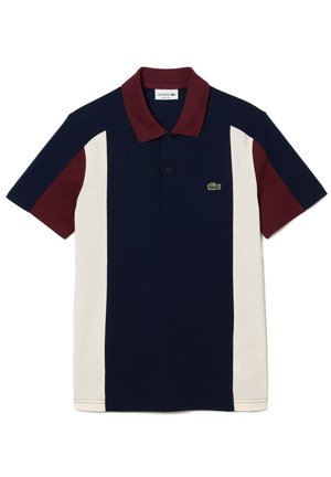 Polo à manches courtes avec un centre bleu marine, des panneaux latéraux crème, un col et des manches bordeaux, et le logo crocodile vert Lacoste sur la poitrine.