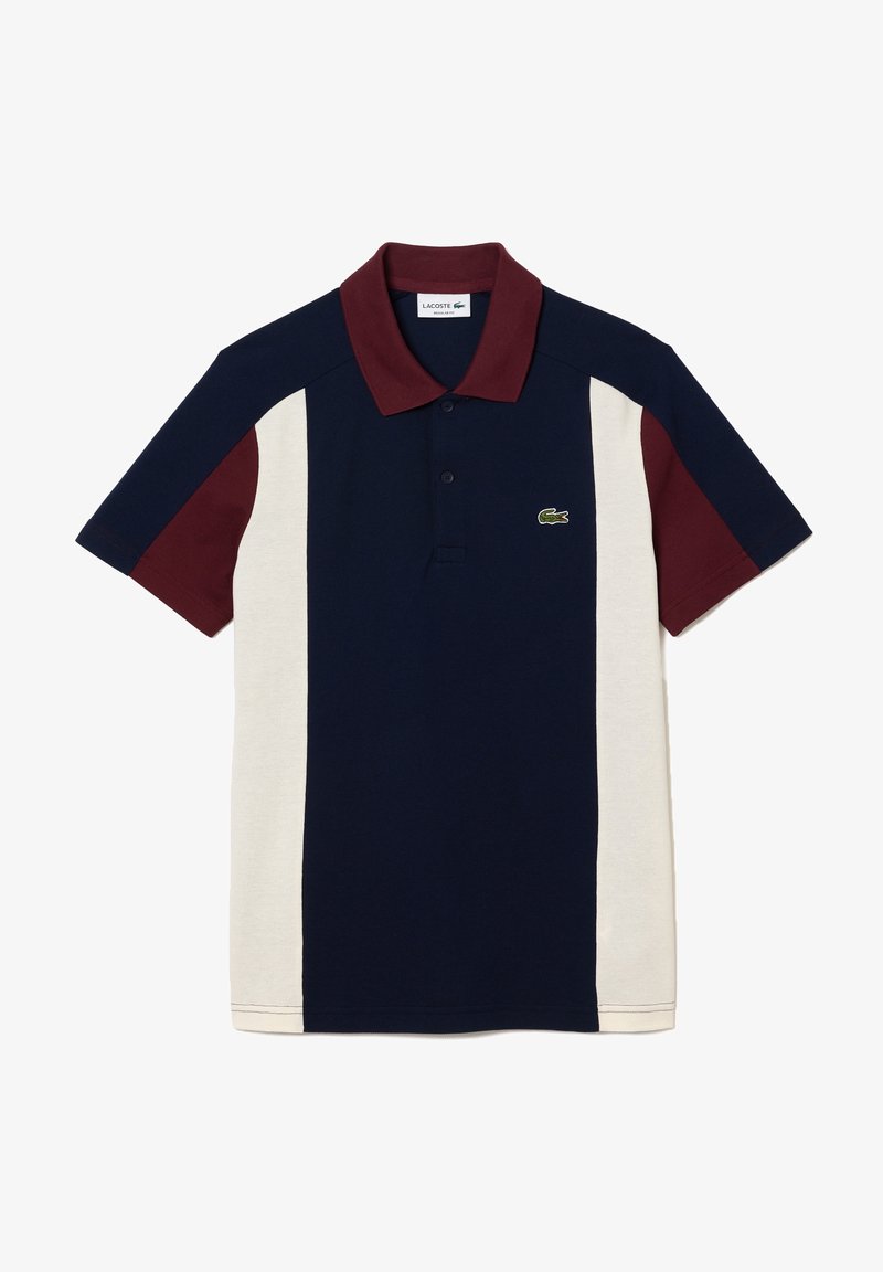 Polo à manches courtes avec un centre bleu marine, des panneaux latéraux crème, un col et des manches bordeaux, et le logo crocodile vert Lacoste sur la poitrine.