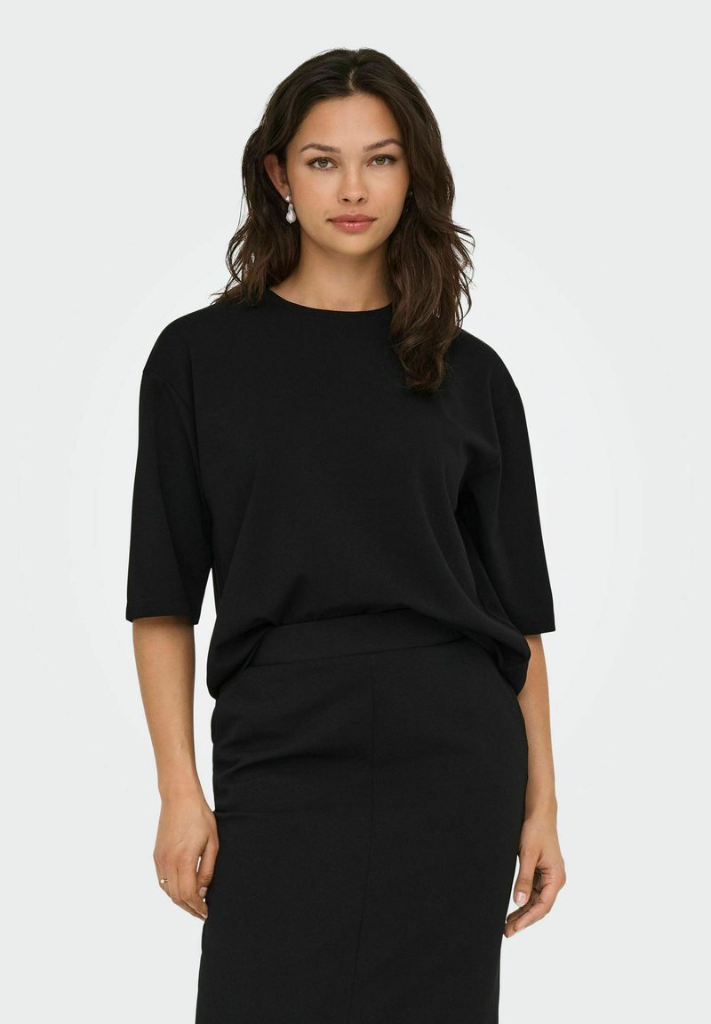 Svart kortärmad skjorta med rund halsringning och avslappnad passform, matchad med en svart pennkjol. Slät textur, minimalistisk design.