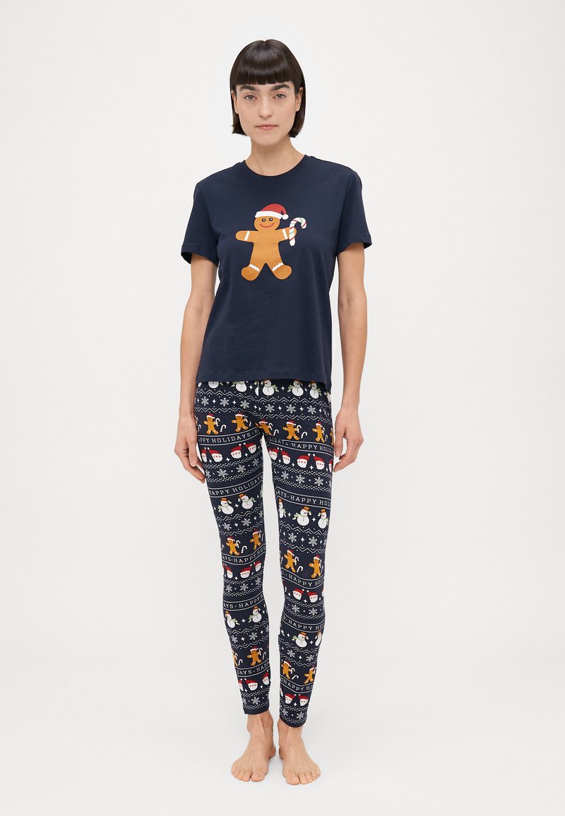 Camiseta navy con un hombre de jengibre sosteniendo un bastón de caramelo, combinada con leggings estampados que muestran motivos navideños en varios colores.