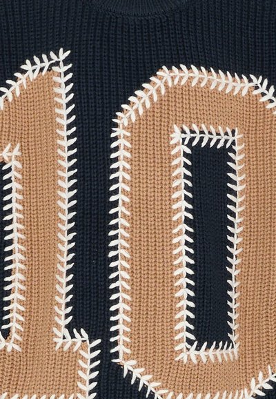 Dzianinowa tkanina z dużą beżową cyfrą "10" obramowaną białym szwem na ciemnoniebieskim tle.