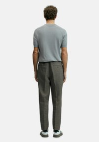 Grijze geribbelde short-sleeve shirt gecombineerd met lichtbruine, op maat gemaakte broeken en witte sneakers. De outfit heeft een minimalistisch ontwerp met subtiele texturen.