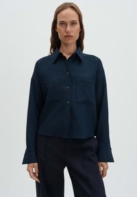 Navy blue button-up shirt with a textured grid pattern, featuring a pointed collar, two chest pockets, and wide cuffs.