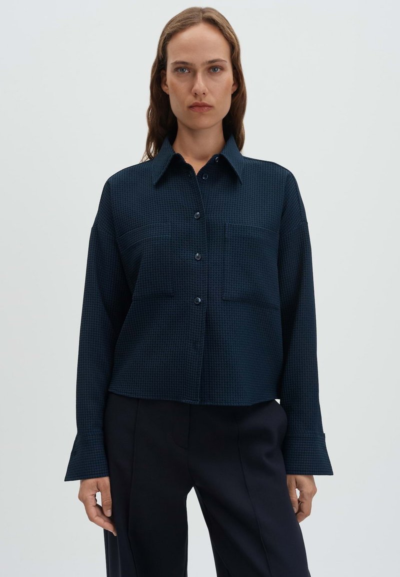 Navy blue button-up shirt with a textured grid pattern, featuring a pointed collar, two chest pockets, and wide cuffs.