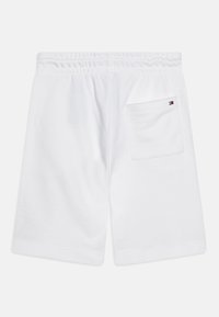 Shorts bianchi con vita elastica e tasca posteriore, caratterizzati da un piccolo logo Tommy Hilfiger su uno sfondo semplice.