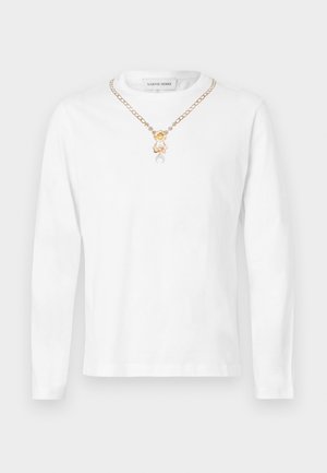 T-shirt branca de manga comprida em algodão, com um colar de corrente dourada com pendente e um corte descontraído.