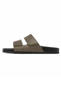 Sandales en cuir marron avec deux straps en velcro ajustables, une semelle intérieure anatomique et une semelle en caoutchouc noir, présentant un design minimaliste.