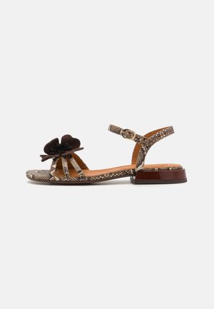Open-toe sandal with a snake print design, brown flower accent, narrow strap, and a low, glossy brown block heel.