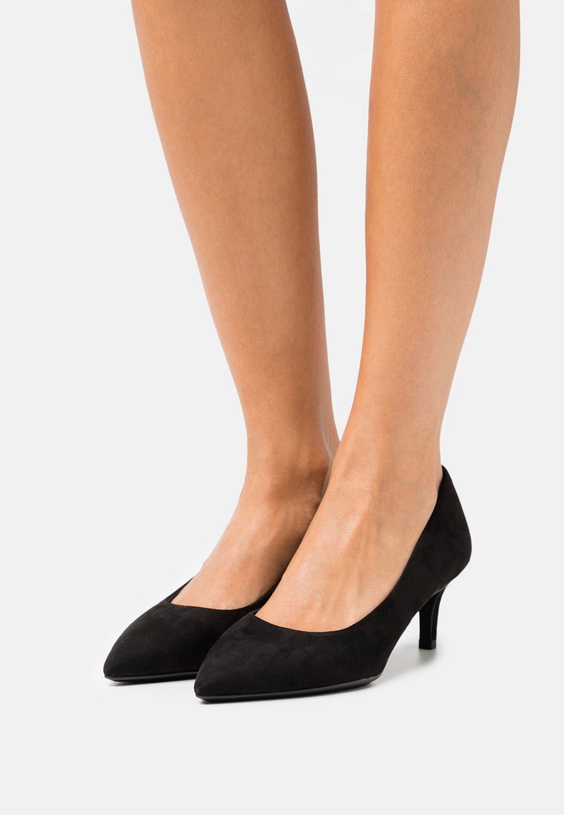 Chaussures à talons hauts en daim noir avec un bout pointu et un talon bas. Texture lisse et design discret de découpes sur les côtés.