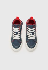 Høye sneakers laget av mørk denimstoff, hvite snøringer, røde detaljer og glidelås på siden med teksturerte gummisåler.