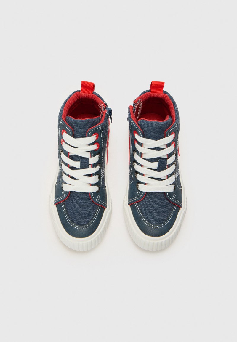 Baskets montantes en tissu en denim foncé, avec des lacets blancs, des accents rouges et une fermeture éclair sur le côté, dotées de semelles en caoutchouc texturé.