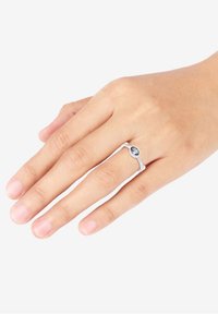 Bague en argent avec une pierre précieuse ovale. Design épuré et minimaliste avec une fine bague. Main positionnée avec des ongles naturels visibles.