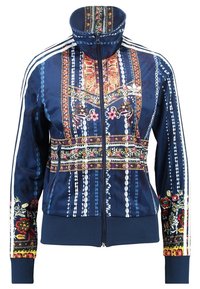 Marinblå zip-up jacka med intrikata blommönster och geometriska mönster, ribbade ärmslut och nederkant samt kontrasterande vita ränder längs axlarna.