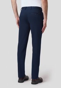Granatowe spodnie wykonane z gładkiego, trwałego materiału, o dopasowanym kroju, klasycznych kieszeniach i subtelnych detalach przeszycia.